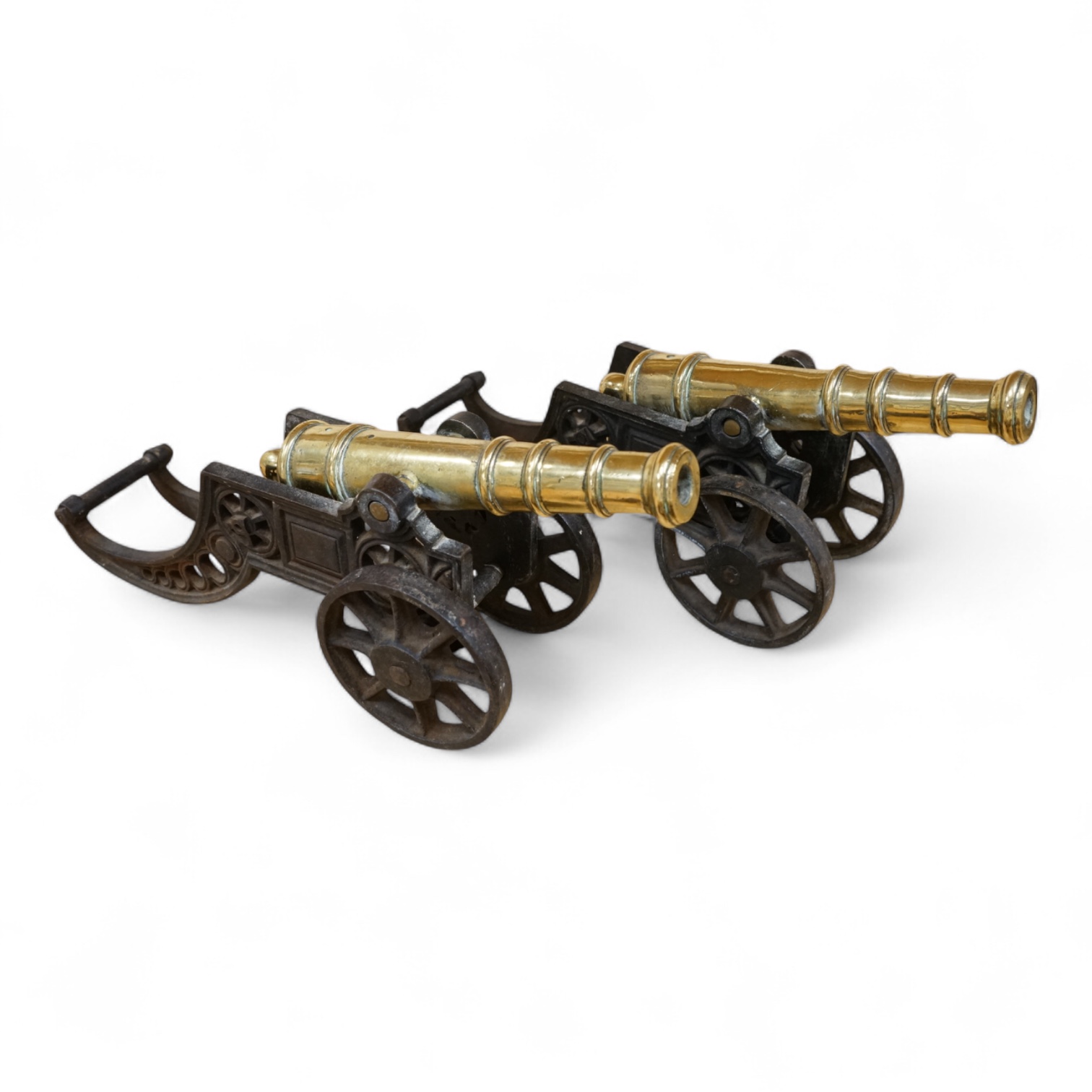 A decorative pair of brass model cannons, with turned barrels, 29cm overall, on cast iron pierced carriages with pierced wheels, overall length 46cm
